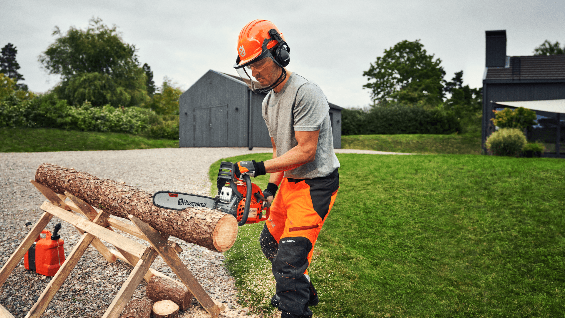man with chainsaw in big backyard cutting log